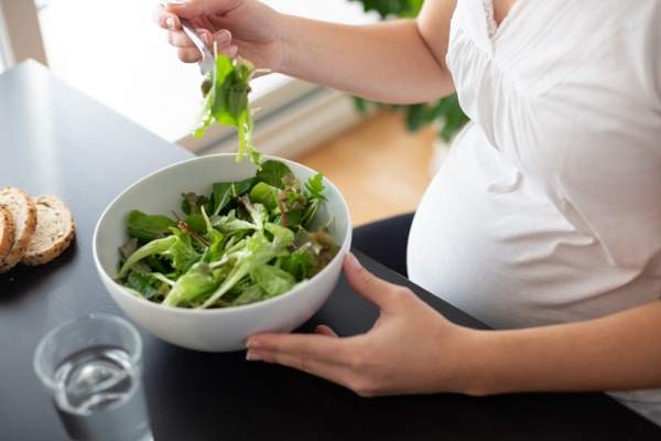 donna incinta che mangia un'insalata