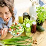 Donna che gusta un’inalata con lattuga, pomodori e tofu, assumendo una sana dose quotidiana di fibre alimentari