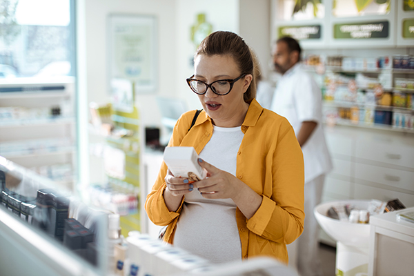 Donna incinta in farmacia che acquisisce un farmaco usufruendo del ticket di esenzione ricetta farmaci