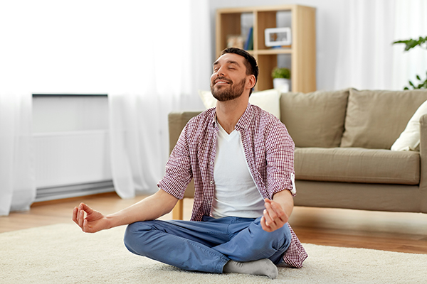 Giovane uomo che gestisce lo stress praticando yoga per prevenire la comparsa di eritema