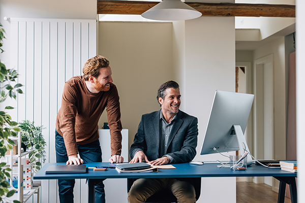 Colleghi che conversano in ufficio davanti alla scrivania, tentando di contrastare l’assenza di movimento fisico