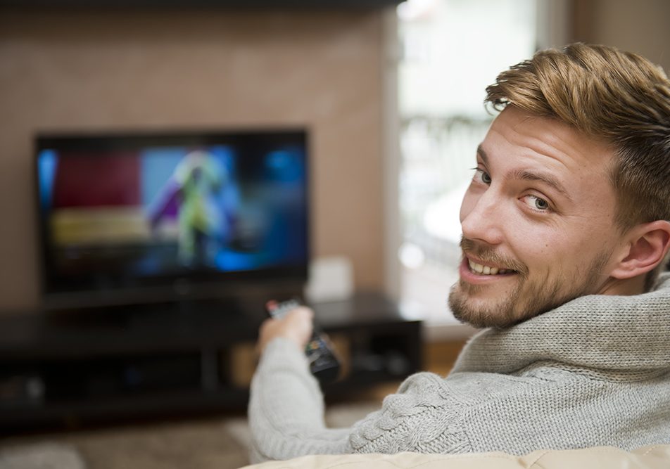 Uomo seduto sul divano nel salotto di casa che conduce uno stile di vita sedentario