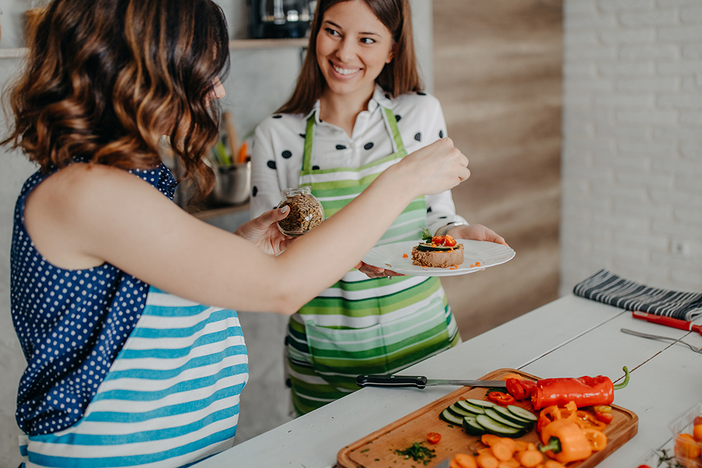 Amiche in cucina che indossano il grembiule e preparano una ricetta ricca di Omega 3 con tonno e semi di lino
