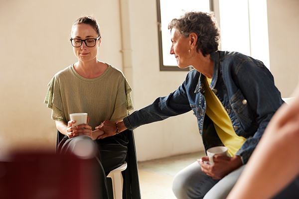 Donna che si sta sottoponendo a dei cicli di terapia durante una terapia di gruppo che riceve supporto emotivo da un’altra paziente
