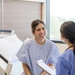 Giovane paziente in una sala ospedaliera che riceve buone notizie dall’infermiera sul suo recente trapianto