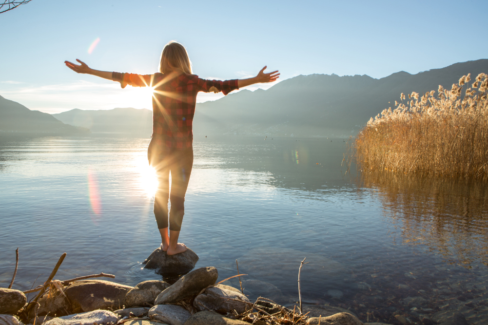 Donna su una pietra davanti a un lago, che trova l'equilibro per i suoi ormoni femminili
