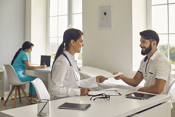 Paziente in ospedale che riceve dalle mani della dottoressa il referto della visita effettuata per diagnosticare le cisti al pancreas