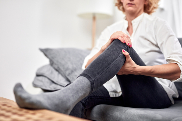Donna seduta sul divano si tocca le gambe gonfie un dei sintomi dello scompenso cardiaco