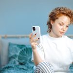 Donna a letto che riceve dal medico, per via telefonica, un consulto sulla reazione allergica che sta riscontrando sulla pelle