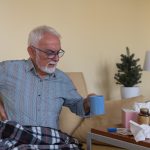 Anziano seduto sul divano con dolori tipici dei sintomi iniziali dell'insufficienza renale