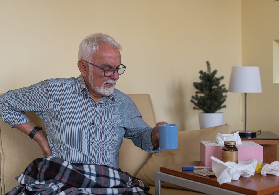 Anziano seduto sul divano con dolori tipici dei sintomi iniziali dell'insufficienza renale