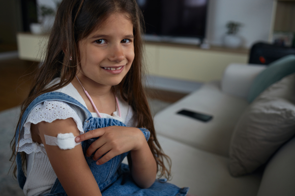 Bambina sorridente con cerotto sul braccio dopo aver fatto vaccino antinfluenzale
