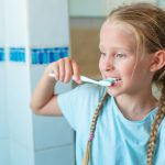 Bambina si lava i denti con dentifricio con fluoro