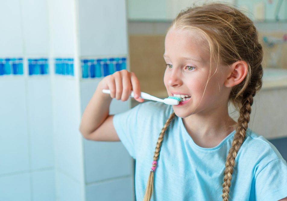 Bambina si lava i denti con dentifricio con fluoro