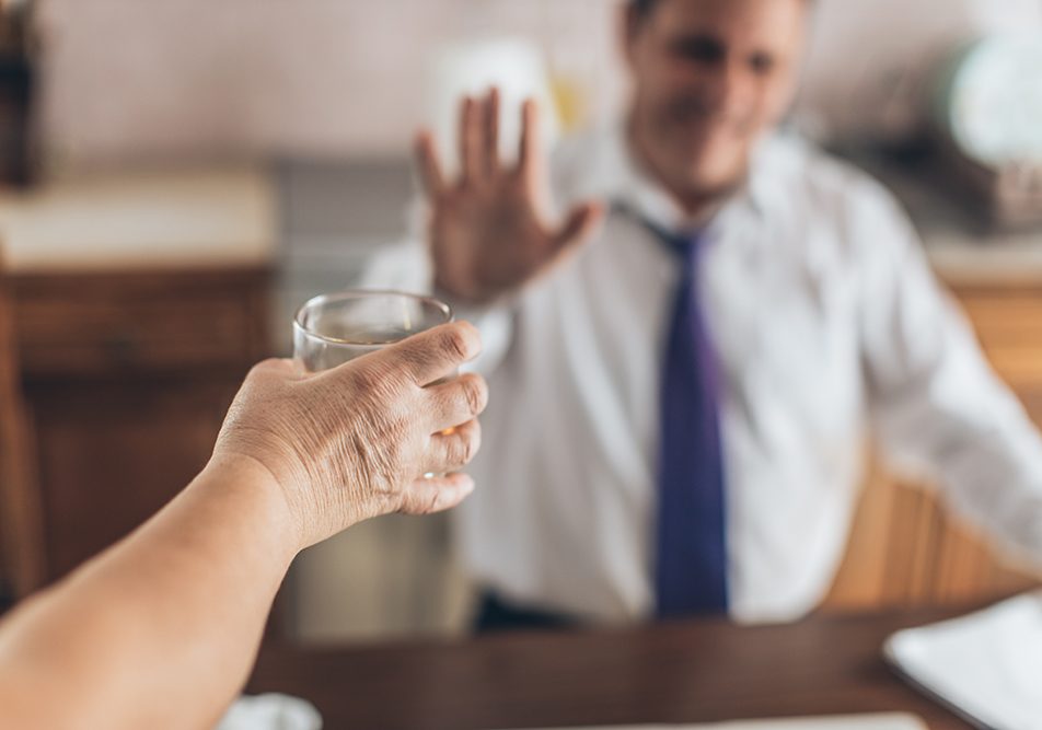 Businessman seduto alla scrivania che rifiuta il consumo combinato di alcol e psicofarmaci