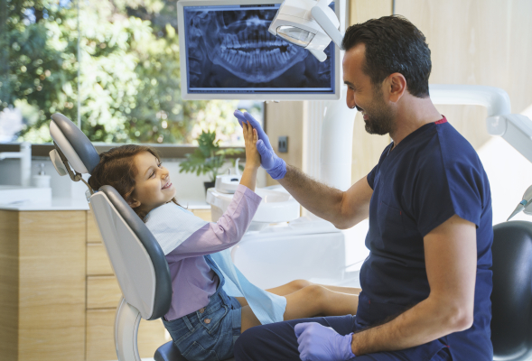Dentista con piccola paziente fornisce consigli per fluoro bambini