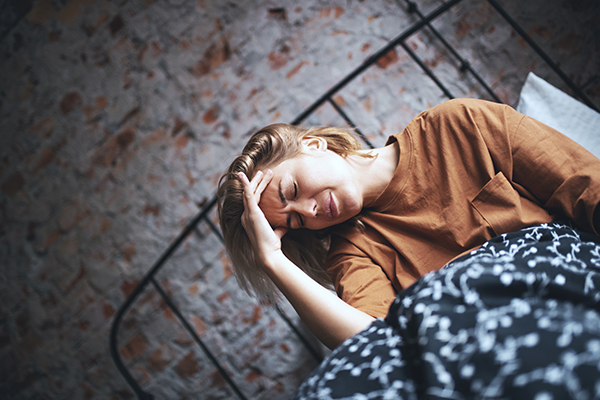 Donna a letto al mattino in stato di confusione mentale che avverte i sintomi dell’epilessia, tra cui la confusione mentale