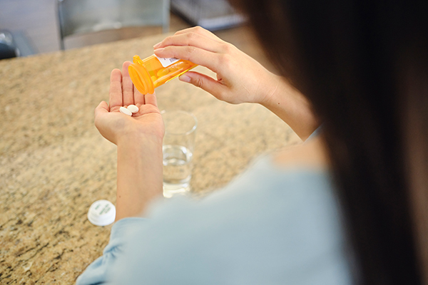 Donna in cucina che assume farmaci prescritti dal medico per la prevenzione di un attacco epilettico