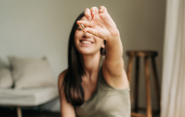 Giovane donna con in mano integratori che assume in estate