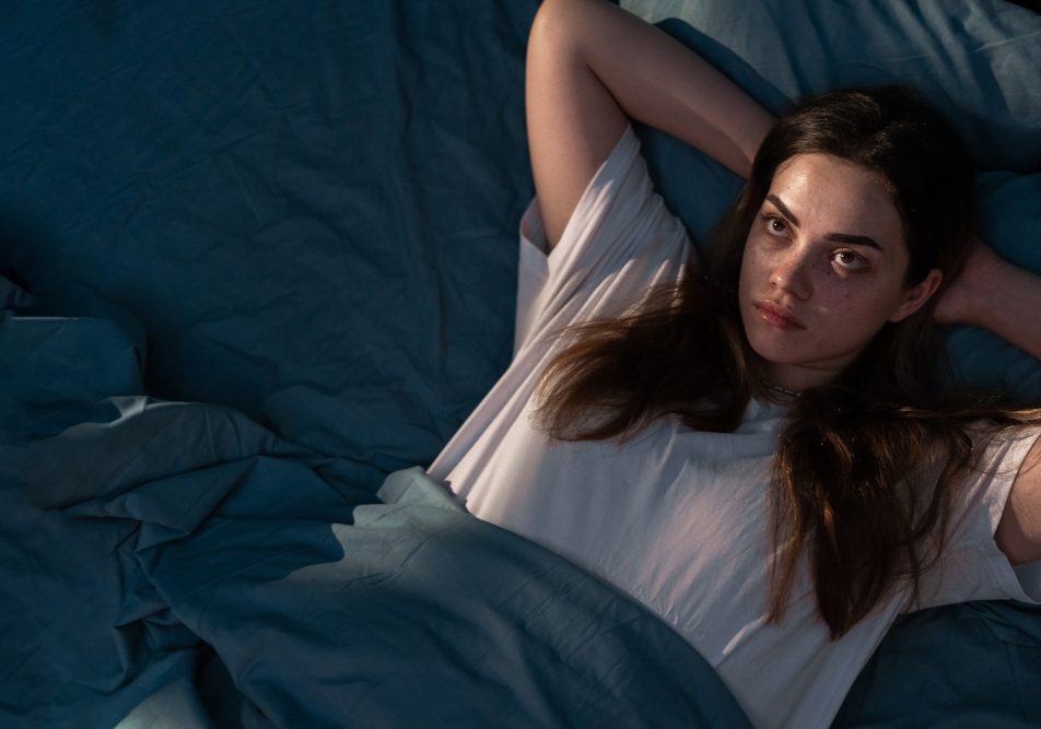 donna-che-manifesta-ansia-notturna-con-sintomi-fisici Giovane donna a letto che ha difficoltà a rilassarsi, tra i sintomi fisici dell'ansia notturna
