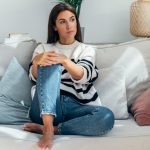 Donna seduta sul divano di casa che manifesta stanchezza da ansia