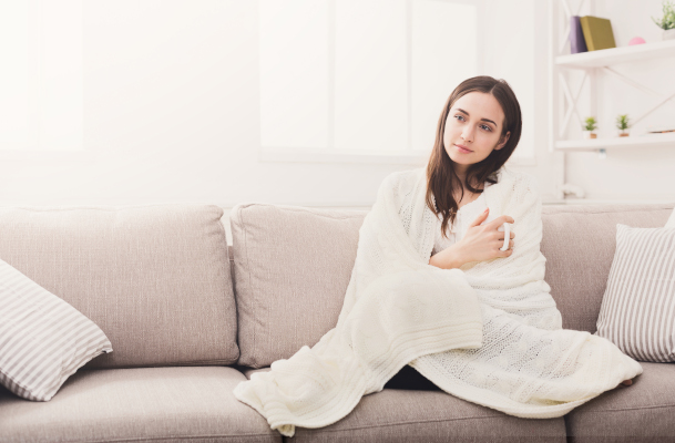 Giovane donna con una coperta sulle spalle che sente i brividi di freddo per l'ansia