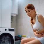 Donna con sindrome dell’ovaio policistico in lavanderia, tentando di attenuare i dolori al ventre