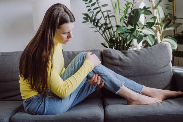 Giovane donna con spasmi muscolari seduta sul divano