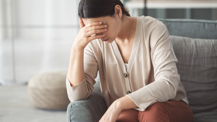 Donna seduta sul divano, con segnali di stanchezza mentale