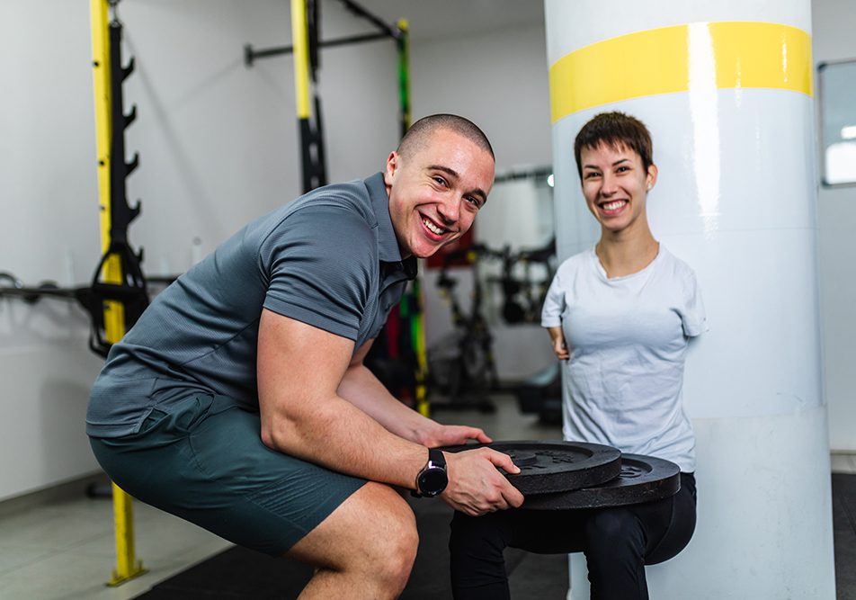 Donna disabile in palestra che sia allena per le competizioni paralimpiche grazie al supporto del suo allenatore di fiducia