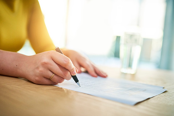 Donna al tavolo di lavoro che firma la pratica per la richiesta del congedo per cure invalidi