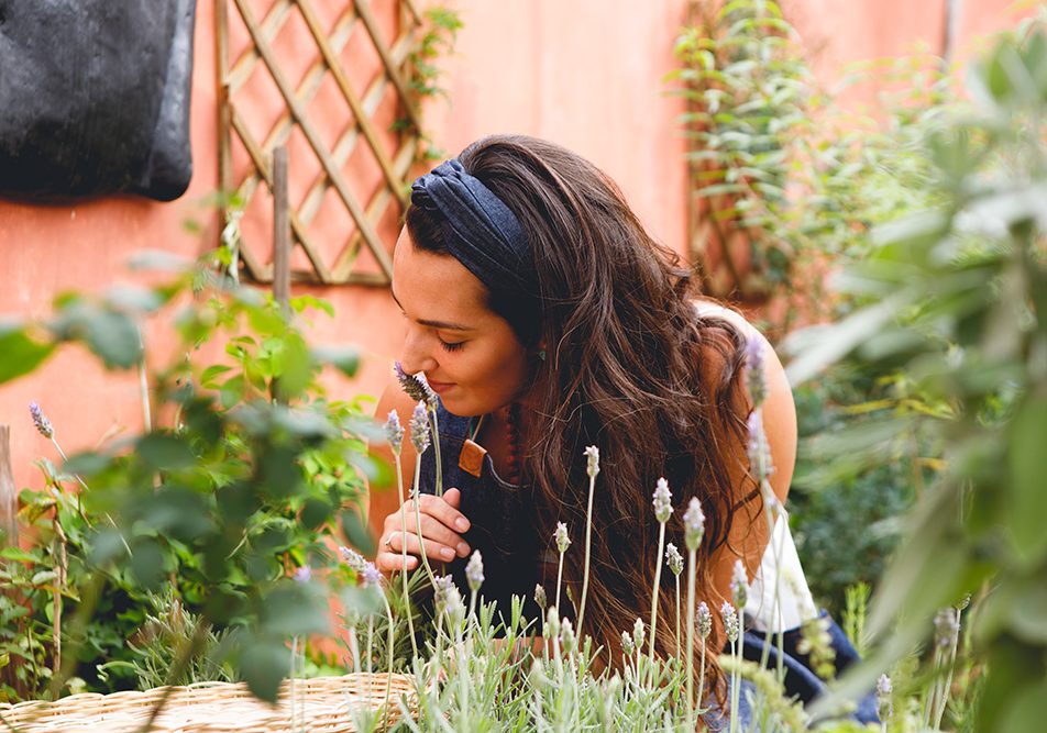 Donna nel cortile di casa che raccoglie ingredienti per produrre ansiolitici naturali senza la necessità della ricetta medica