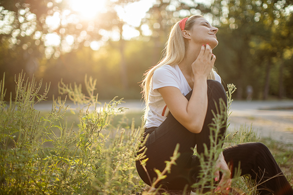 Donna seduta in un prato che avverte prurito, sintomo comune di allergia ai pollini