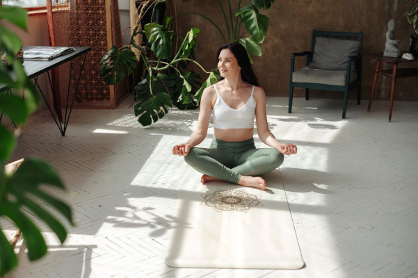 Giovane donna, in una stanza con piante verdi, pratica yoga, utile anche per esercizi per la schiena