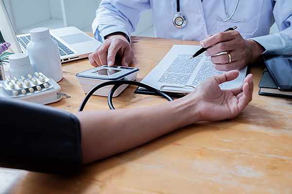 Dottore che misura la pressione alla paziente per il rilascio del certificato medico non agonistico