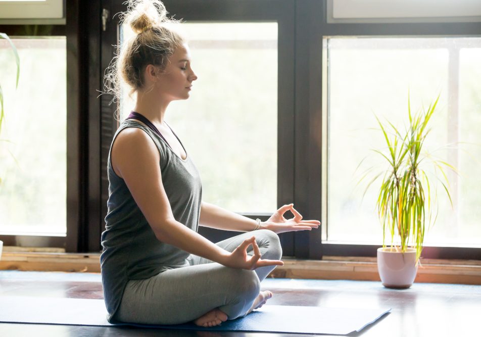 Giovane donna in casa sua pratica yoga come ginnastica dolce