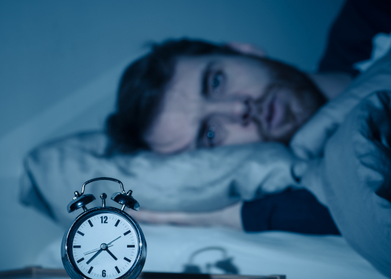 Giovane uomo a letto che soffre di insonnia, tra gli effetti collaterali della sertralina