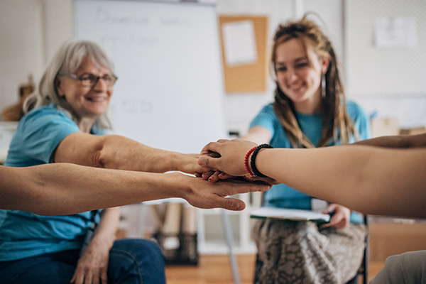 Gruppo di donatori di midollo osseo durante un incontro in associazione, i cui membri si tengono le mani in segno di cooperazione e di solidarietà