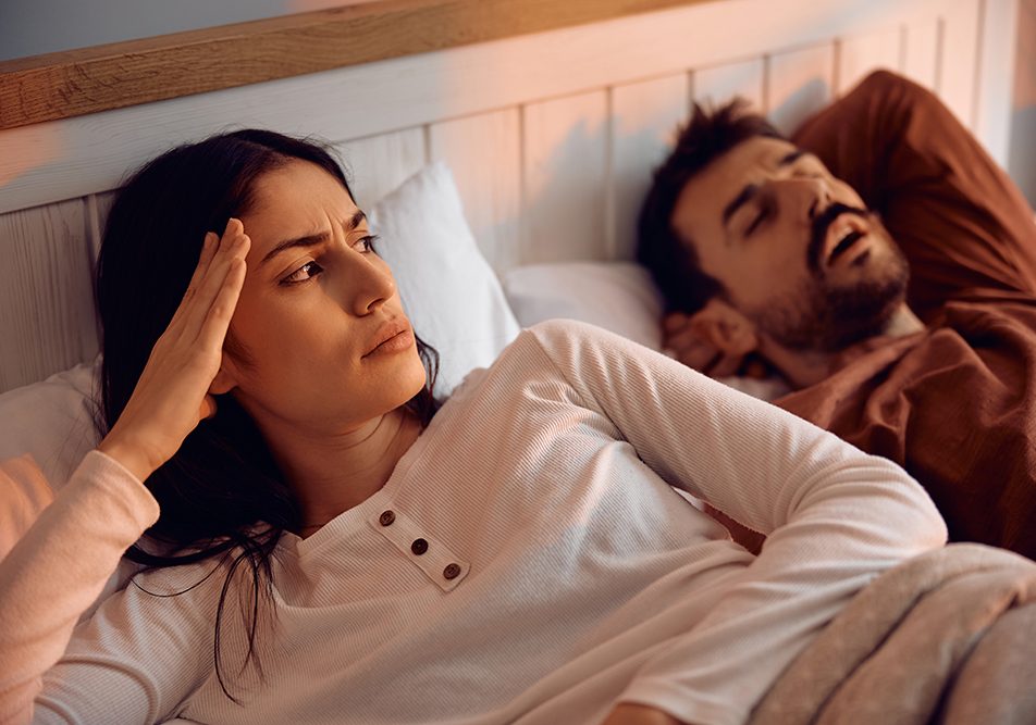 Una coppia in camera da letto all’alba, di cui la donna non riesce a riposare a causa dell’uomo con apnee ostruttive del sonno