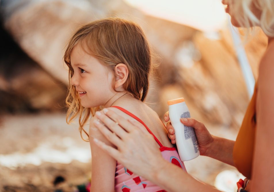 Mamma e figlia in estate sotto il sole proteggono con la crema e assorbono vitamine e minerali