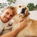 Padrone felice sul divano in compagnia del suo cane golden retriever guarito dalla dermatite interdigitale