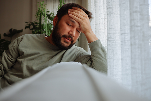 Uomo a casa sul divano che manifesta un peggioramento dei sintomi depressivi a causa del consumo associato di benzodiazepine e alcol