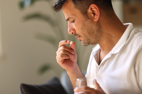 Uomo a casa che assume il trattamento prescritto dal suo medico, evitando di consumare insieme antidepressivi e alcol
