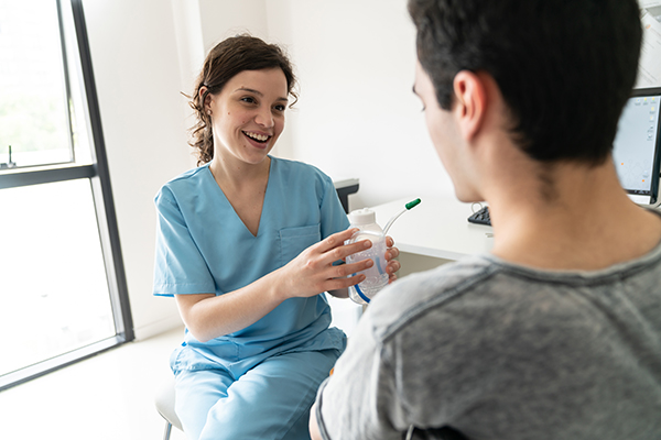 Uomo adulto insieme a fisioterapista che compie un esercizio di respirazione con l’ausilio dello spirometro per imparare a convivere serenamente con la fibrosi cistica