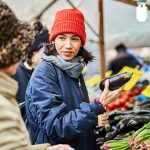 Amiche al mercato rionale che acquistano verdura autunnale, tra cui melanzane