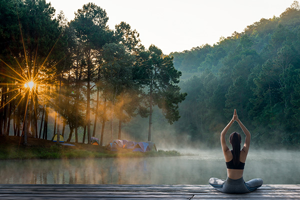 Donna che acquisisce benefici fisici, mentali ed emotivi grazie alla pratica dello yoga in mezzo alla natura