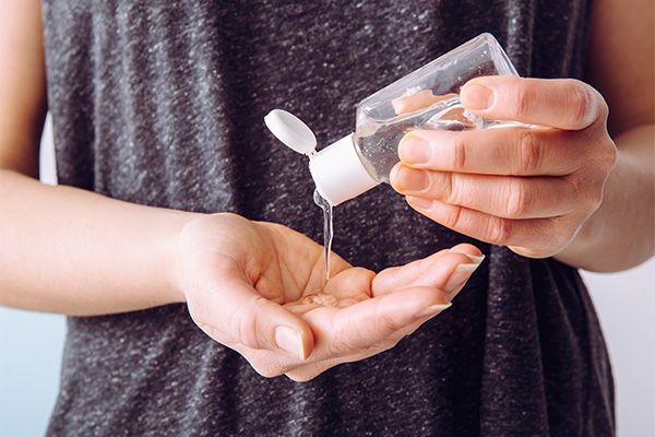 Donna che applica un gel disinfettante sulle mani e contribuisce all’immunità di gregge contro il Covid-19 adottando buone pratiche di prevenzione