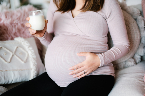 Donna incinta beve un bicchiere di latte freddo, tra i rimedi per il bruciore di stomaco in gravidanza