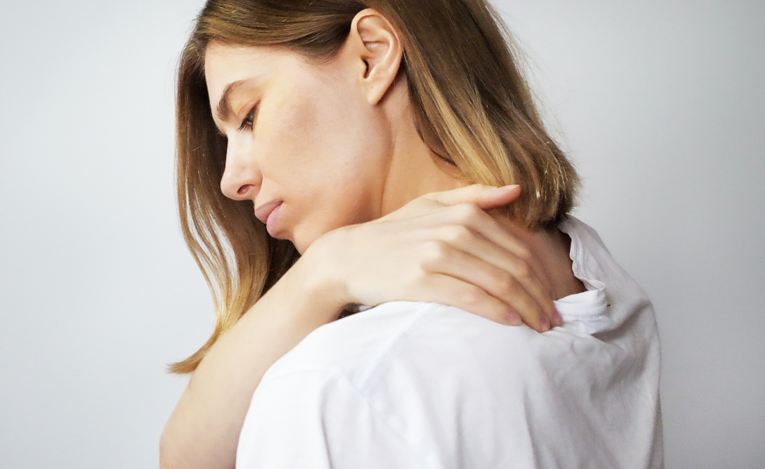 Donna con la mano sulla spalla che soffre di malattie reumatiche