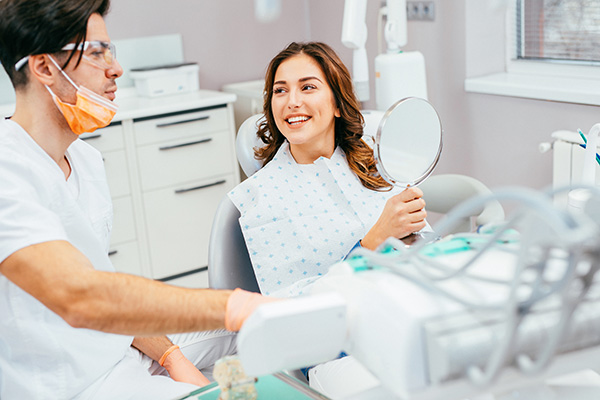 Donna dal dentista che osserva il suo sorriso allo specchio dopo avere concluso un’accurata pulizia dei denti